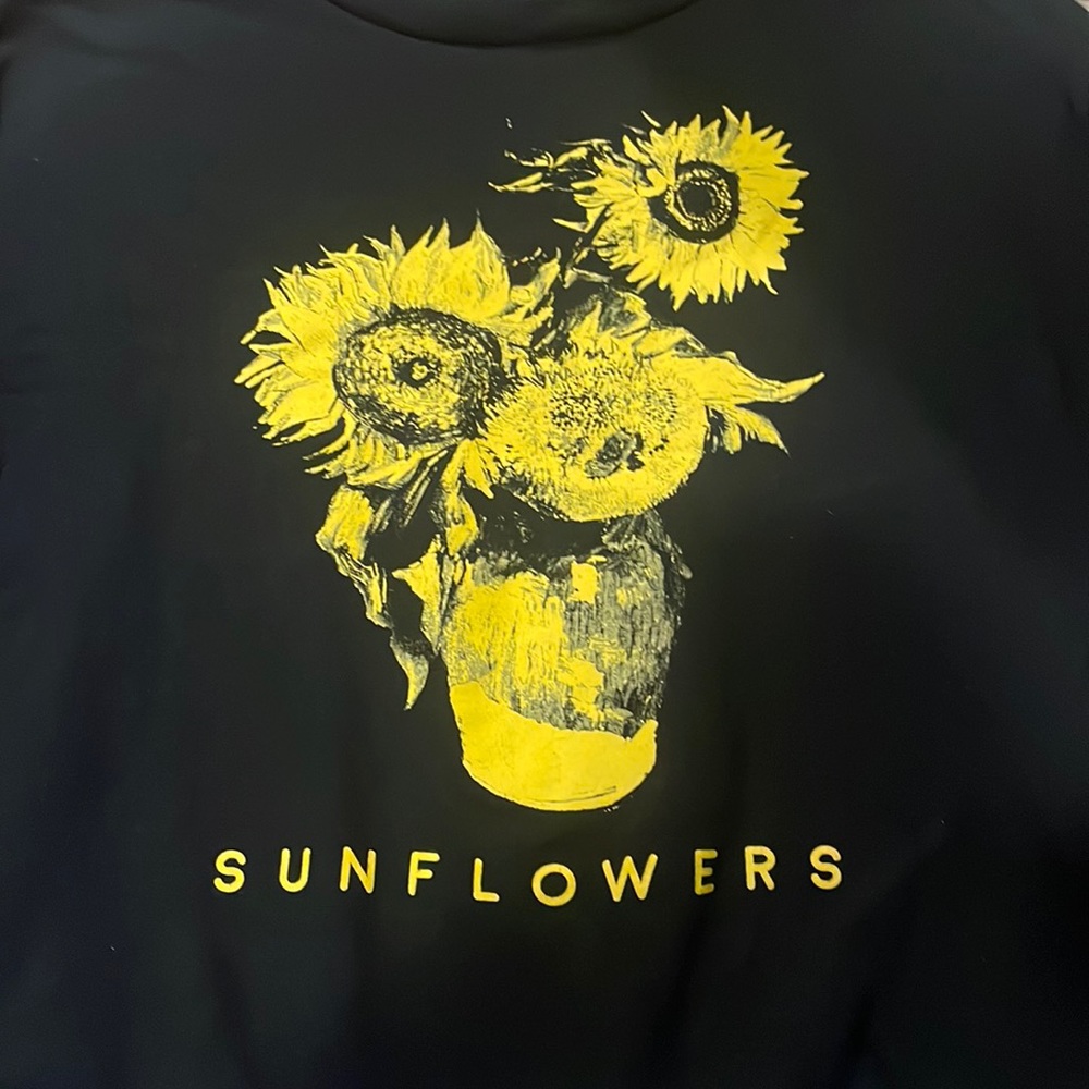 A black  long sleeve sweatshirt with yellow sunflowers in the center